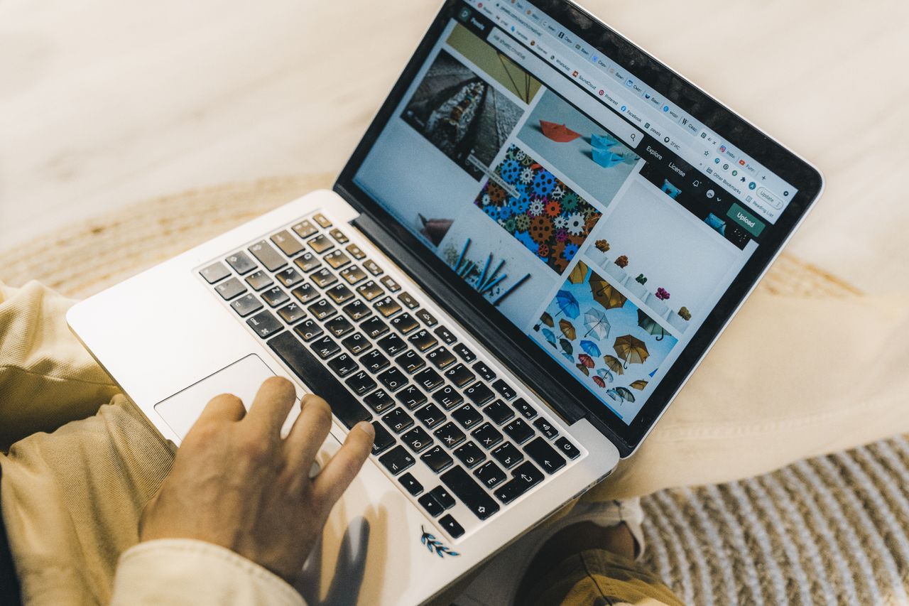 heros-img A person using a laptop to browse stock photo websites. Freelancing work in a cozy setting.